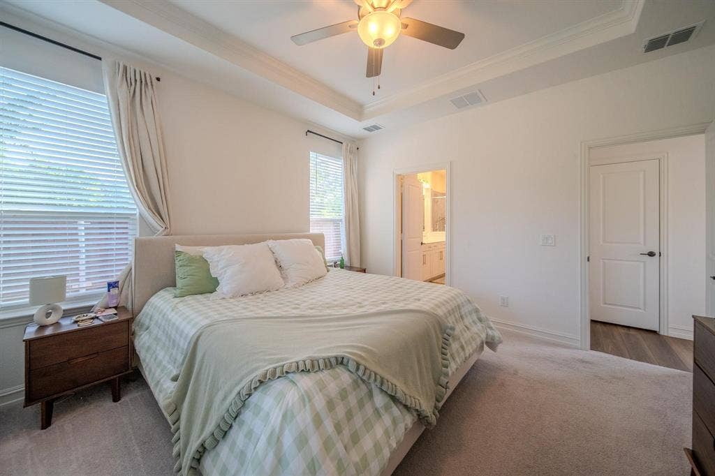 4629 Golden Gate Way, Garland, TX 75043 Tray ceiling with a ceiling fan light fixture, light-colored carpeting, two windows with blinds, and an interior door with dark hardware