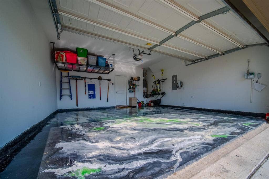4629 Golden Gate Way, Garland, TX 75043 Garage featuring a decorative epoxy floor finish, overhead storage racks, and white interior walls
