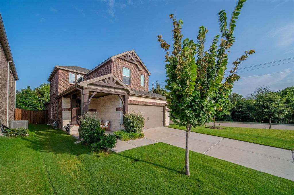 4629 Golden Gate Way, Garland, TX 75043 Brick exterior with stone accents, covered front porch, attached garage, concrete driveway, and established landscaping