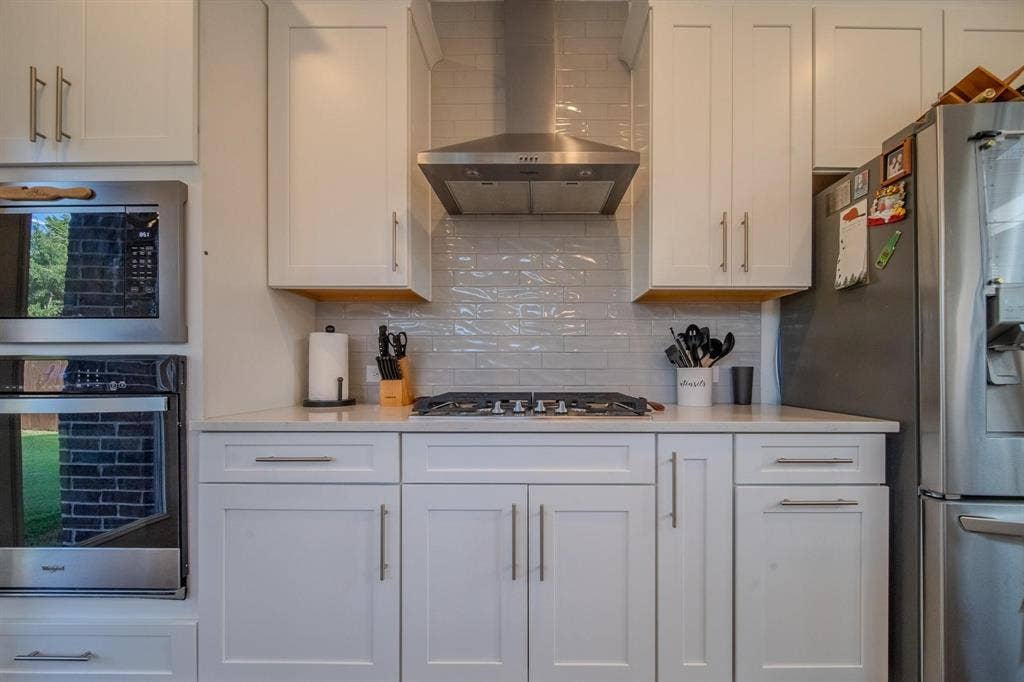 4629 Golden Gate Way, Garland, TX 75043 White cabinetry with stainless steel hardware, built-in microwave, integrated oven, and a gas range with an overhead exhaust hood