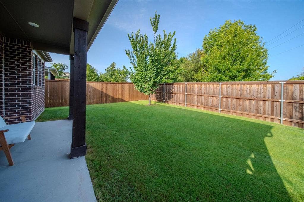 4629 Golden Gate Way, Garland, TX 75043 Expansive lawn with wood privacy fencing, concrete patio, and brick exterior
