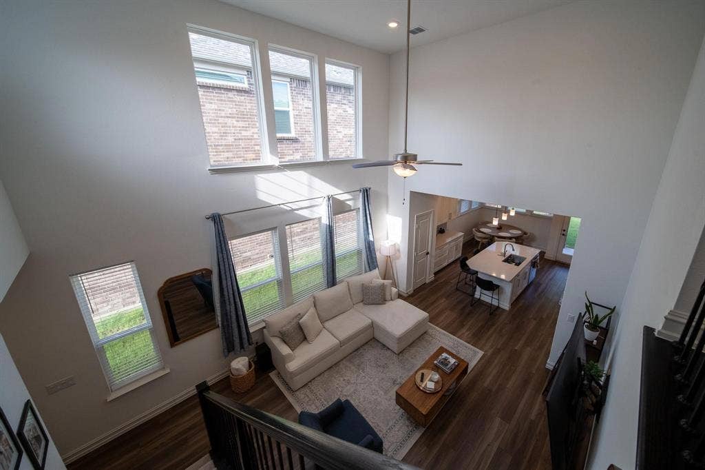 4629 Golden Gate Way, Garland, TX 75043 Two-story living area with high ceilings, multiple windows, wood-finish flooring, and a ceiling fan