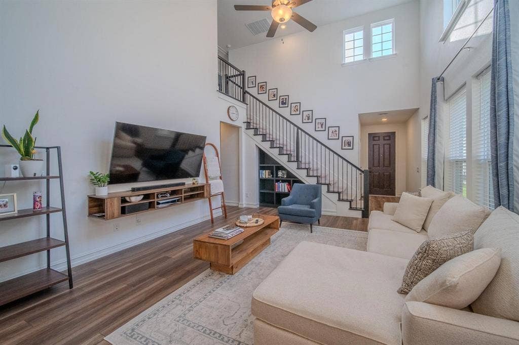 4629 Golden Gate Way, Garland, TX 75043 Two-story living area with wood-finish flooring, a contemporary staircase with dark metal balusters, and a ceiling fan