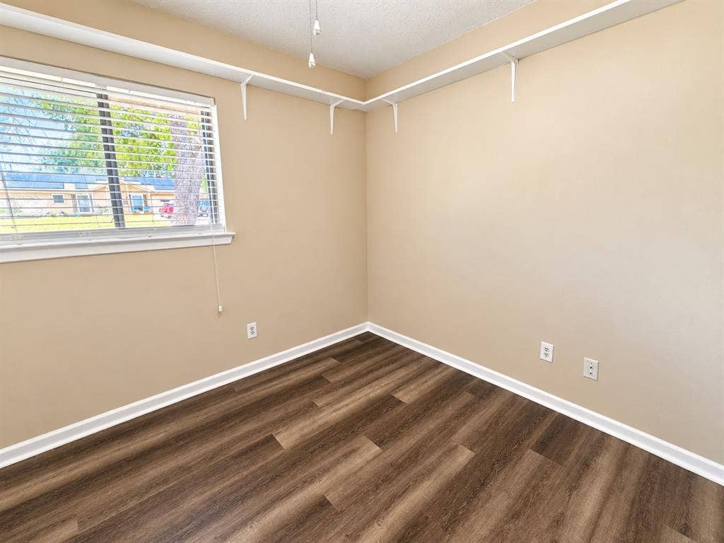 1500 Sherrye Drive, Plano, TX 75074 Wood-finish flooring with white trim, a window featuring horizontal blinds, and corner-mounted shelving