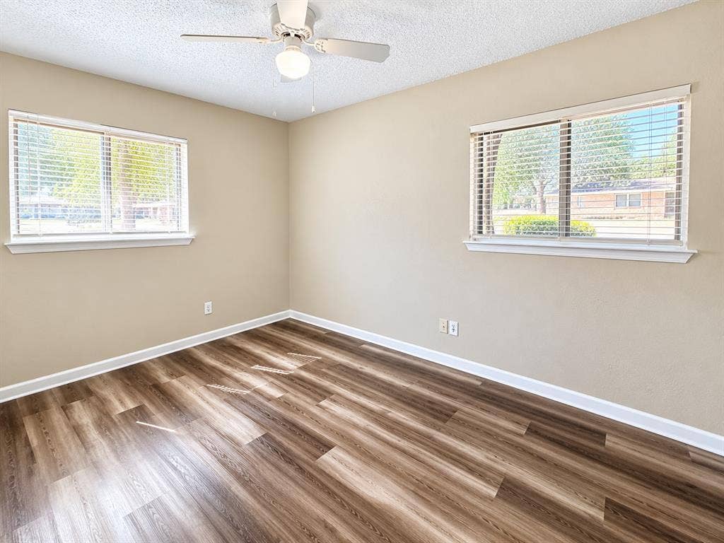 1500 Sherrye Drive, Plano, TX 75074 Wood-finish flooring, two large windows with blinds, ceiling fan with integrated lighting, and neutral wall paint