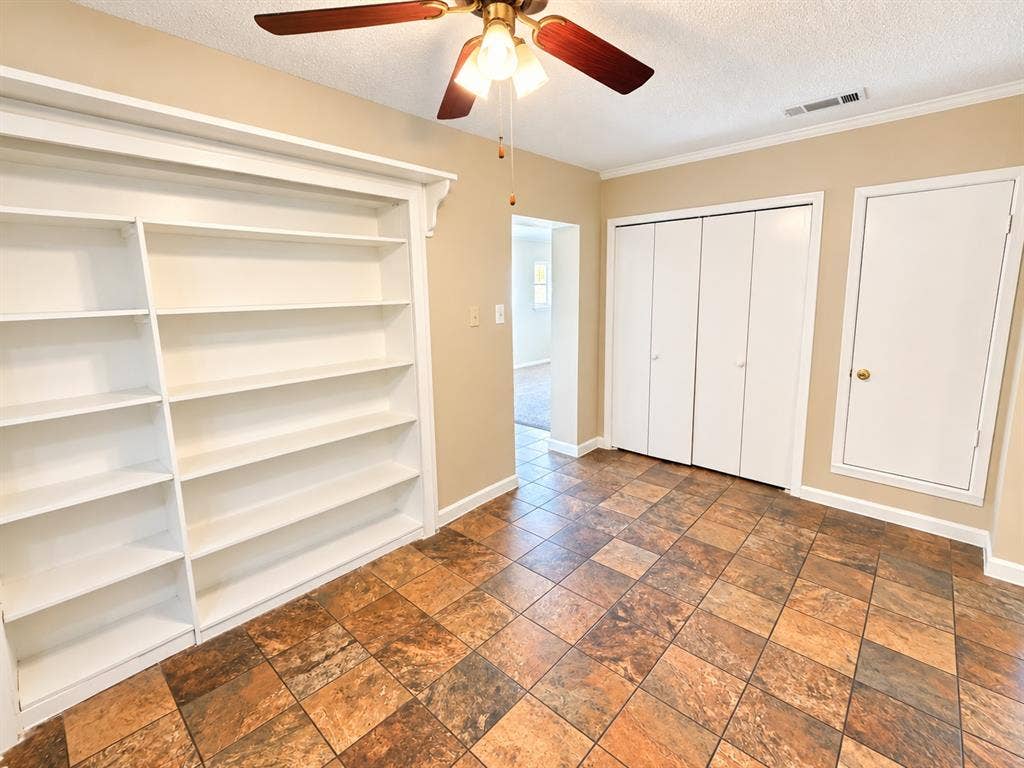 1500 Sherrye Drive, Plano, TX 75074 Built-in white shelving, wood-finish ceiling fan, bi-fold closet doors, and multi-tone square floor tiles