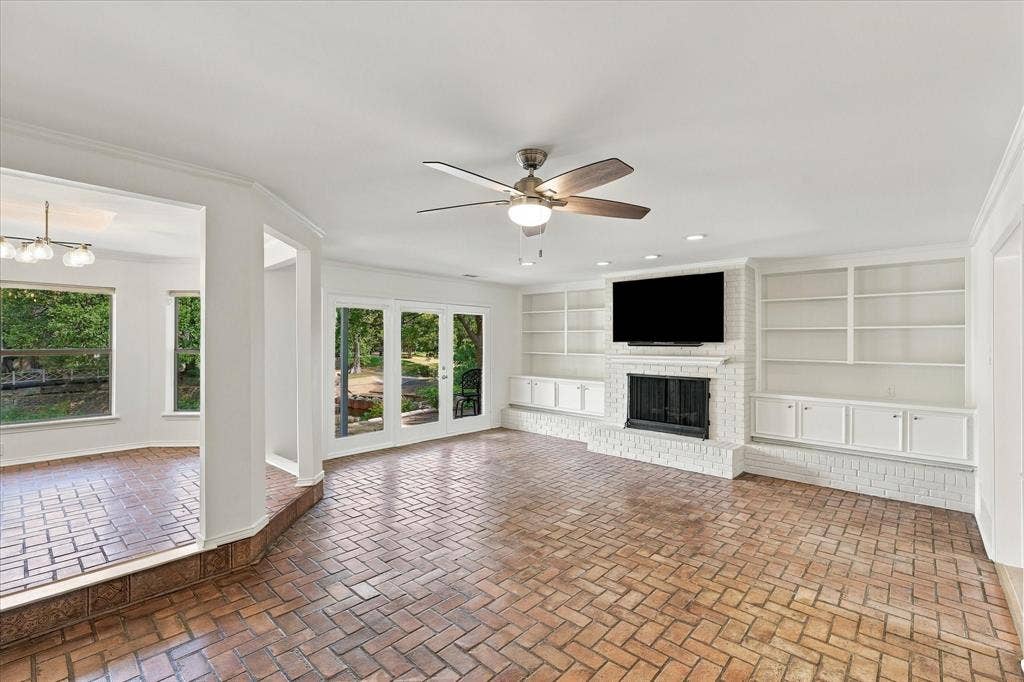 2811 Reedcroft Drive, Farmers Branch, TX 75234 Herringbone brick flooring, white brick fireplace with hearth, built-in shelving, built-in cabinetry, and French doors