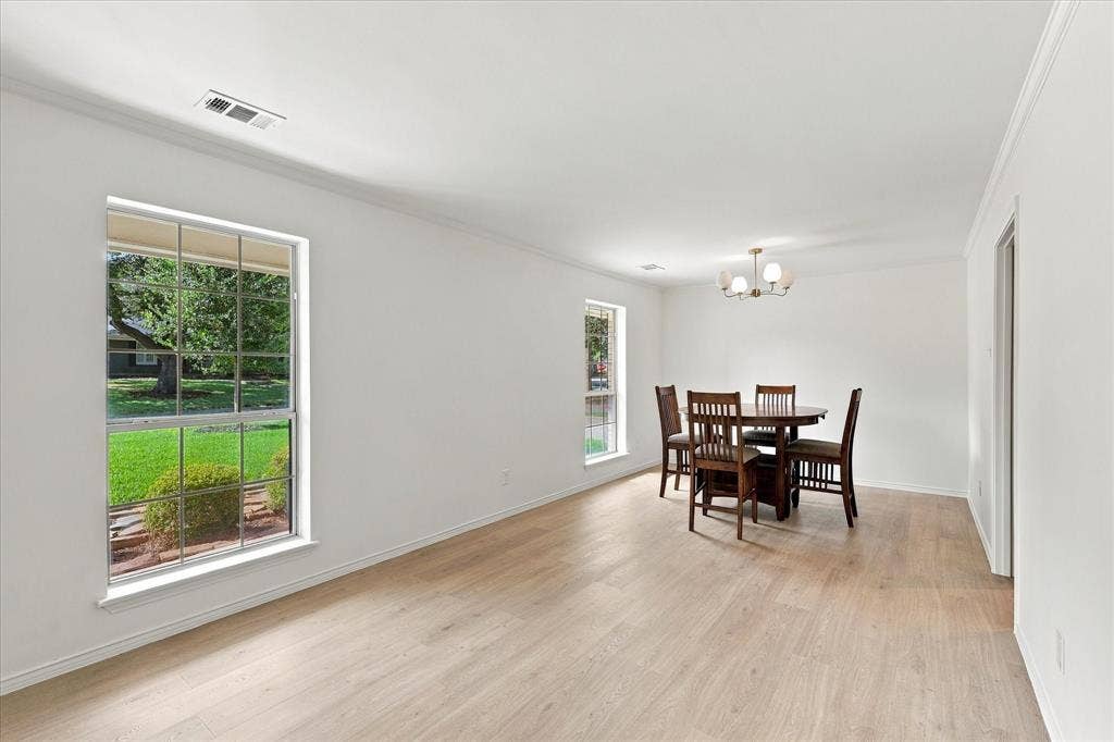 2811 Reedcroft Drive, Farmers Branch, TX 75234 Light wood-finish flooring throughout, white walls, multiple windows, and a chandelier with frosted glass shades