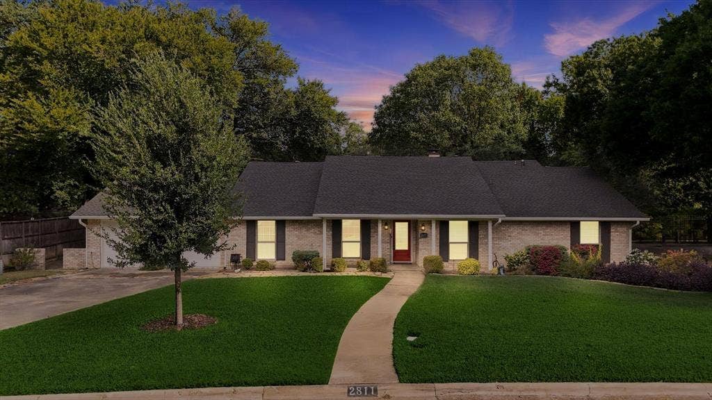 2811 Reedcroft Drive, Farmers Branch, TX 75234 Brick exterior with dark shutters, established landscaping, and a curved concrete walkway