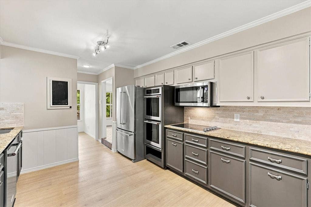 2811 Reedcroft Drive, Farmers Branch, TX 75234 Light wood-finish flooring, stainless steel appliances, two-tone cabinetry, stone countertops, and a tiled backsplash