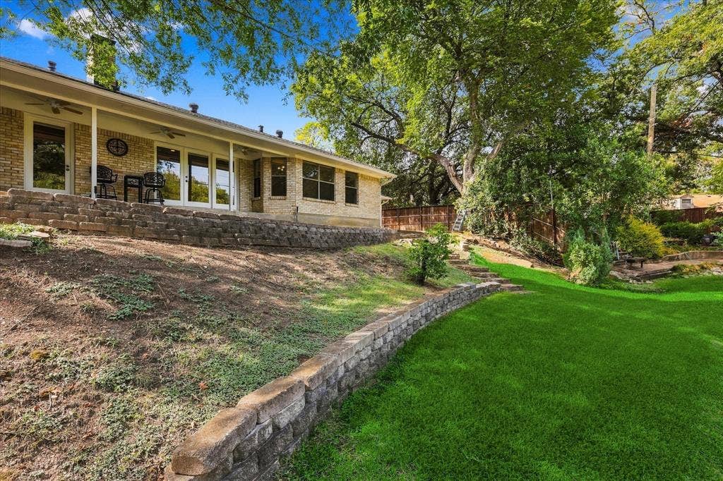 2811 Reedcroft Drive, Farmers Branch, TX 75234 Brick exterior with covered patio, multiple glass panel doors, and tiered landscaping