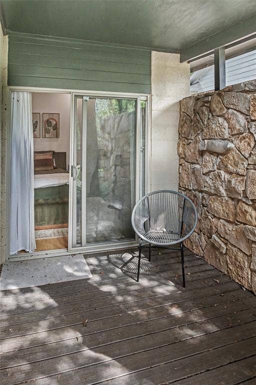 11737 Rogue Way, Dallas, TX 75218 Covered patio off the primary suite featuring wood-finish decking and natural stone wall