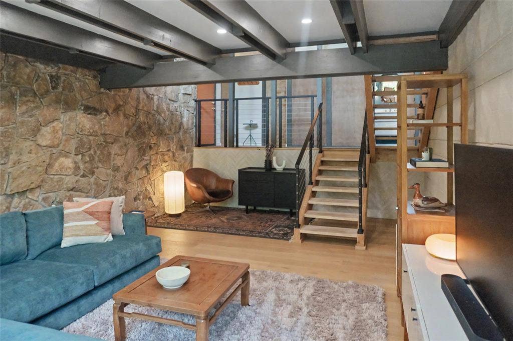11737 Rogue Way, Dallas, TX 75218 Lower-level living room featuring a reading nook, laundry room, and anchored by MCM rock wall