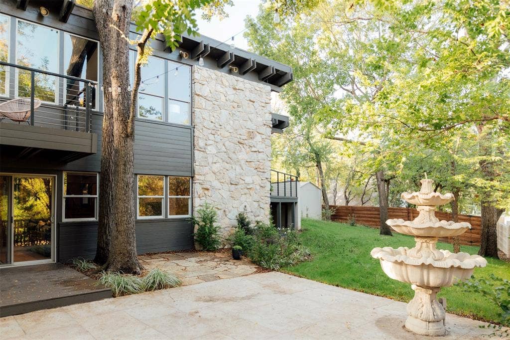 11737 Rogue Way, Dallas, TX 75218 Side patio with tiered fountain, stone wall, and lawn