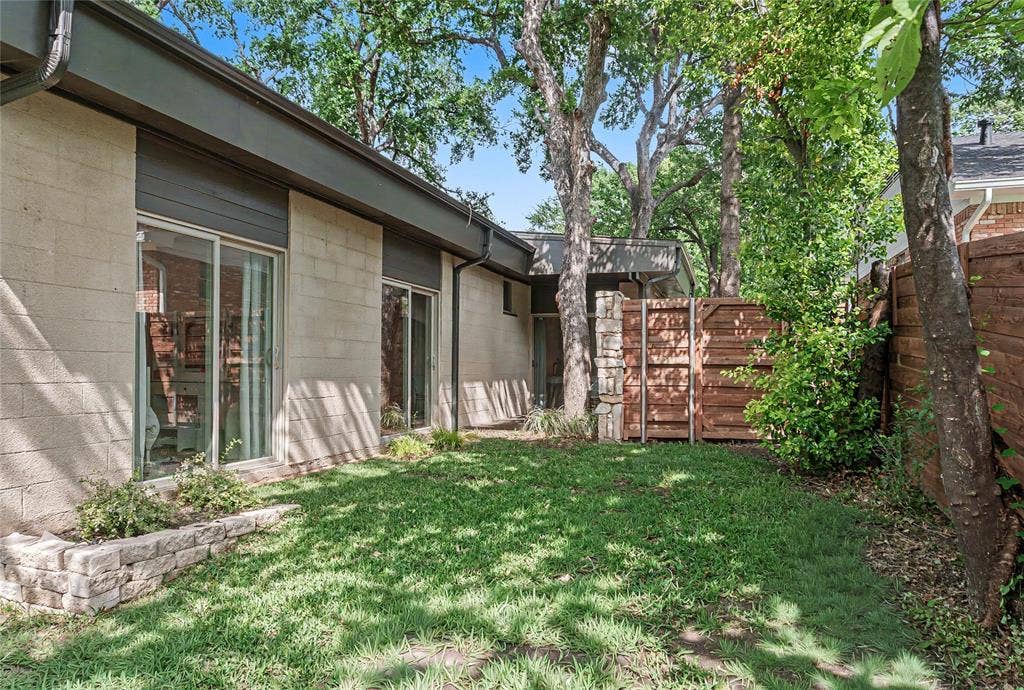 11737 Rogue Way, Dallas, TX 75218 Backyard framed by mature trees and an American cedar fence