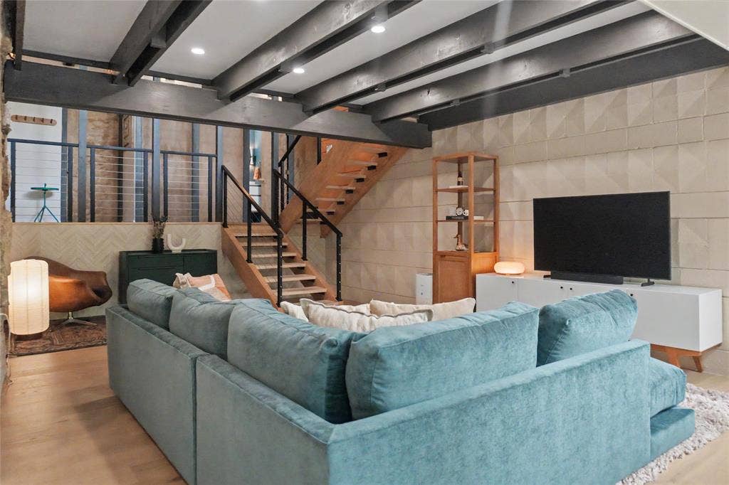 11737 Rogue Way, Dallas, TX 75218 Lower level living room with exposed ceiling beams, geometric textured wall panels, and perfect for movie night