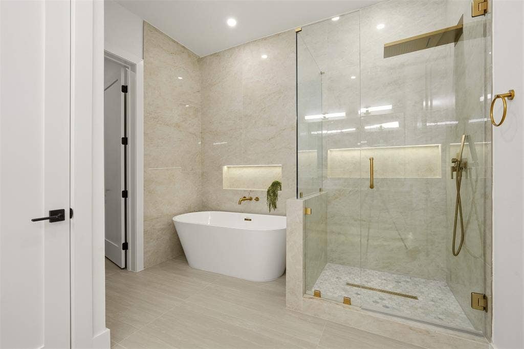 6911 Mohawk, Dallas, TX 75235 Freestanding soaking tub, walk-in shower with glass enclosure, gold-finish fixtures, and light-toned tile flooring