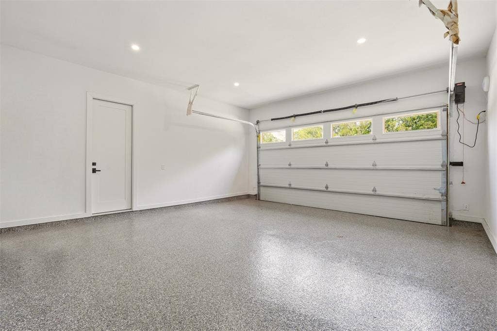 6911 Mohawk, Dallas, TX 75235 Epoxy-coated flooring, recessed lighting, and a white overhead garage door with upper windows