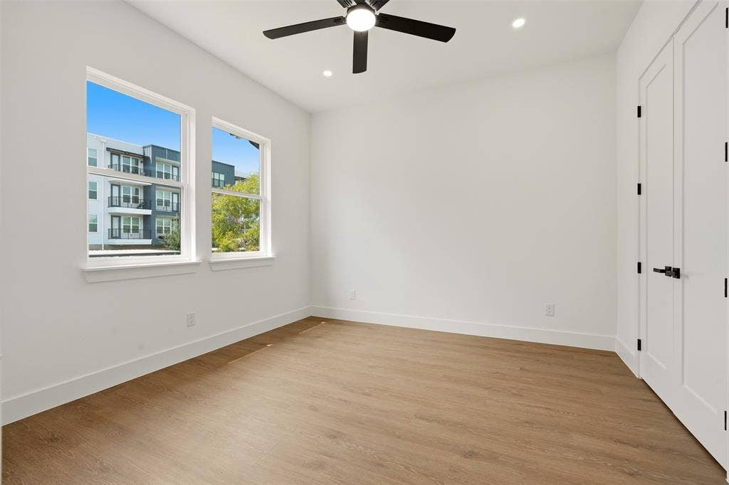 6911 Mohawk, Dallas, TX 75235 Two double-hung windows with white trim, wood-finish flooring, a contemporary ceiling fan, recessed lighting, and a paneled door with matte black hardware