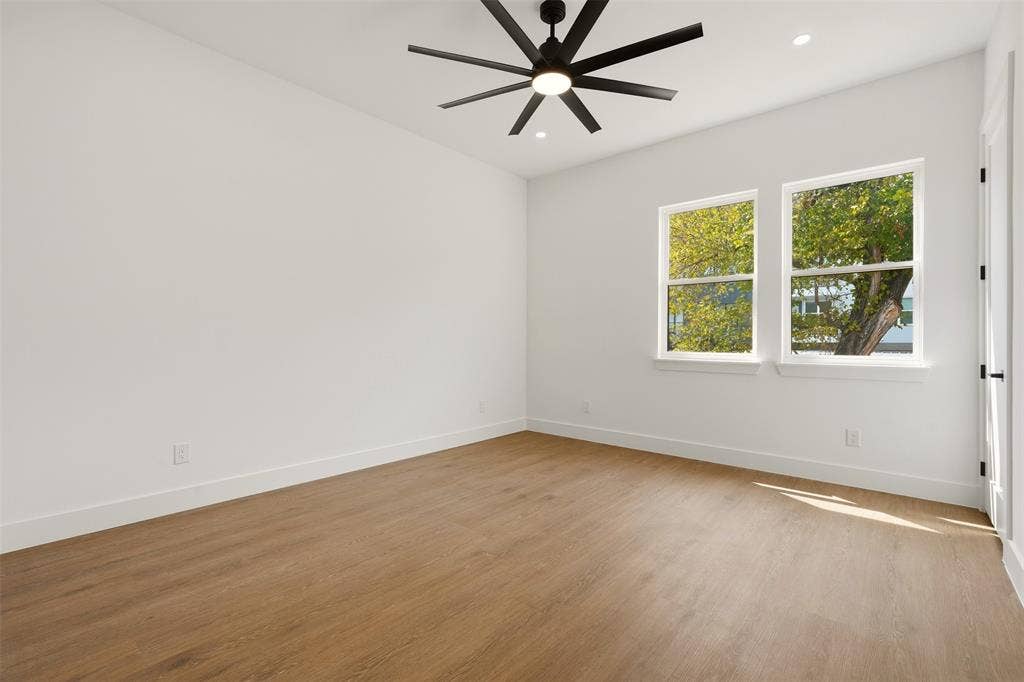 6911 Mohawk, Dallas, TX 75235 Spacious room featuring wood-finish flooring, two large windows, a modern ceiling fan, and recessed lighting