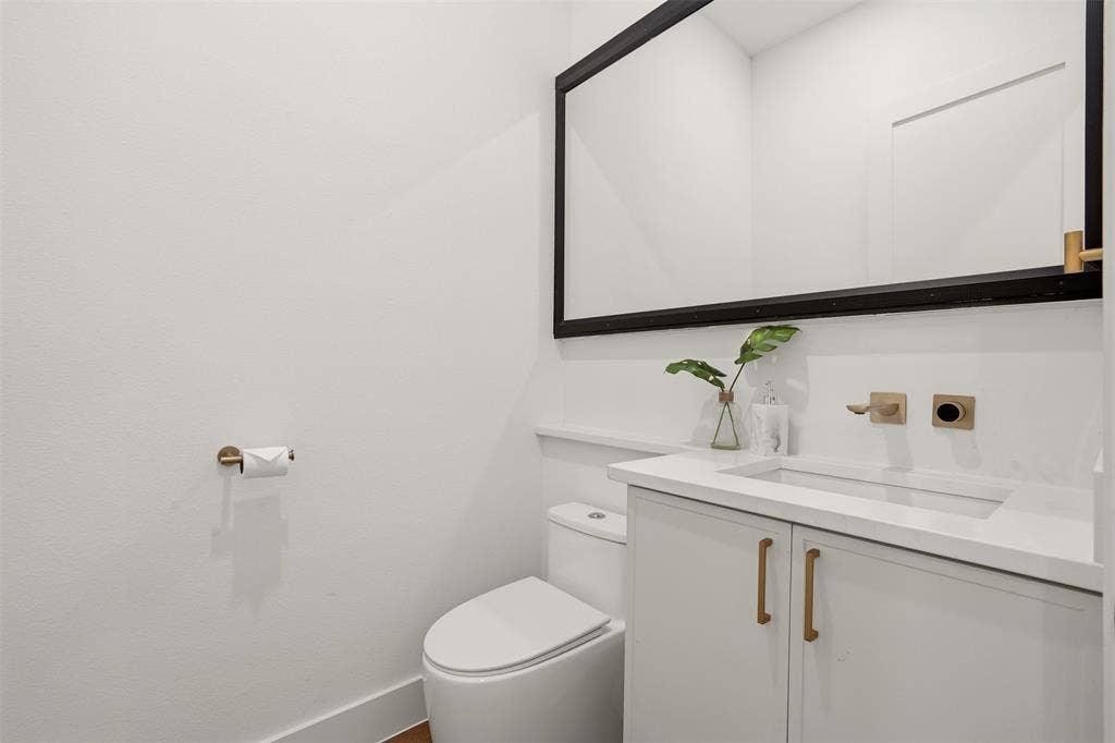 6911 Mohawk, Dallas, TX 75235 White vanity with integrated sink, gold-tone hardware, and a wall-mounted faucet