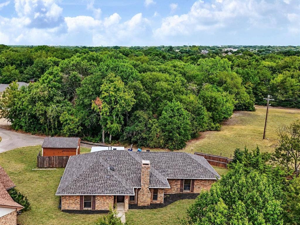 219 N Beltwoods Drive, DeSoto, TX 75115 Brick exterior with a shingle roof, established landscaping, and a detached shed