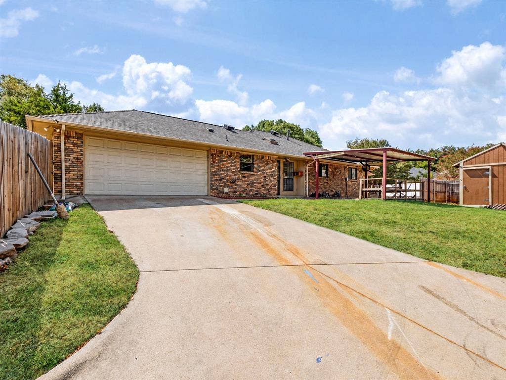 219 N Beltwoods Drive, DeSoto, TX 75115 Brick exterior, attached garage, concrete driveway, wood privacy fence, and an outdoor storage shed