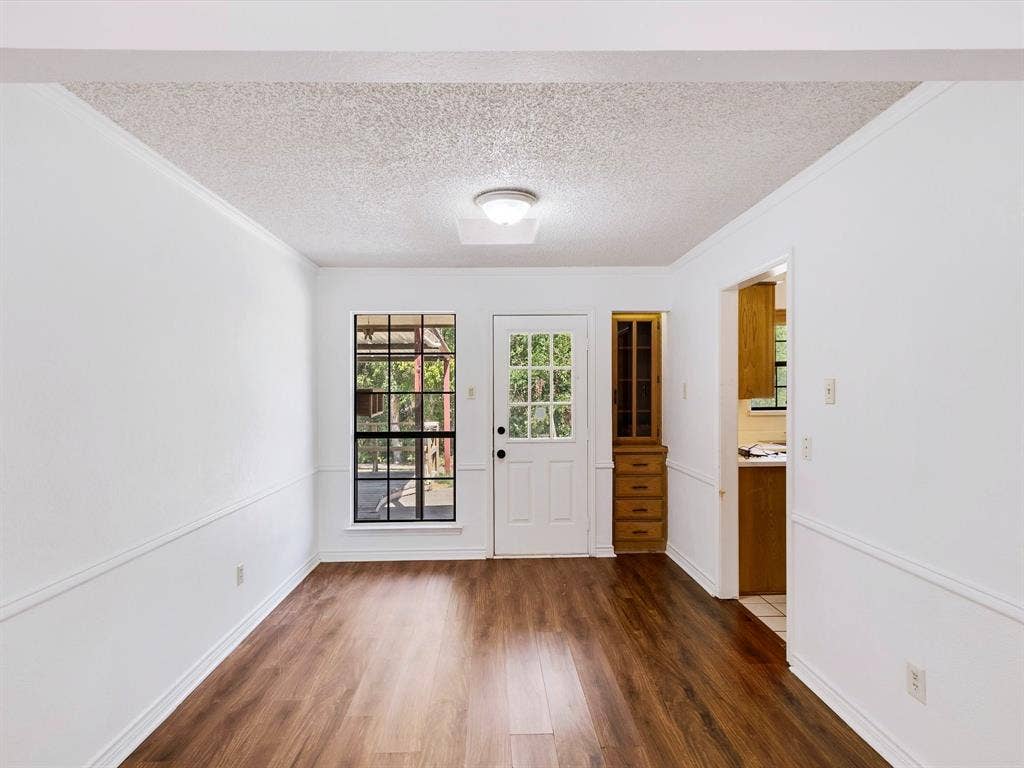 219 N Beltwoods Drive, DeSoto, TX 75115 Wood-finish flooring, white walls with chair rail molding, and a built-in wood cabinet