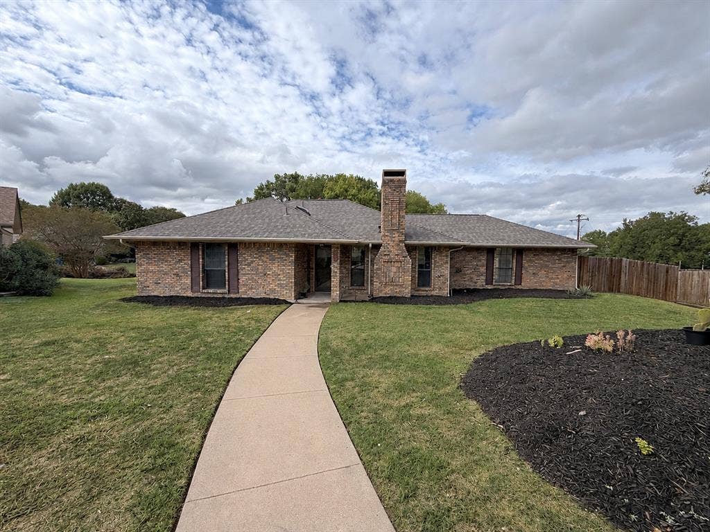 219 N Beltwoods Drive, DeSoto, TX 75115 Brick exterior with a prominent brick chimney, gabled roofline, and a concrete walkway