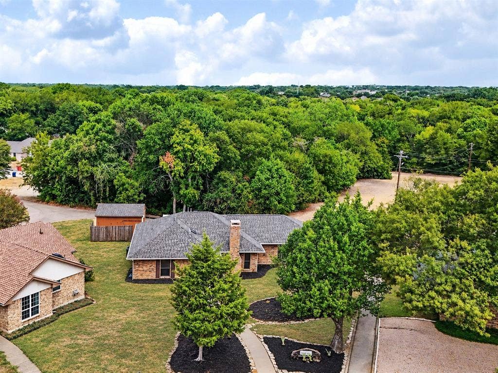 219 N Beltwoods Drive, DeSoto, TX 75115 Brick exterior residence with a gray shingled roof, featuring a brick chimney, and a stone-edged walkway