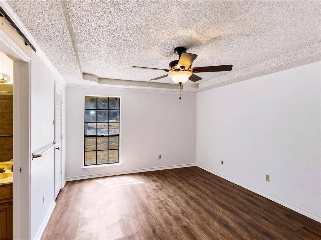 219 N Beltwoods Drive, DeSoto, TX 75115 Wood-finish flooring, white walls, tray ceiling, ceiling fan with integrated lighting, and a multi-pane window