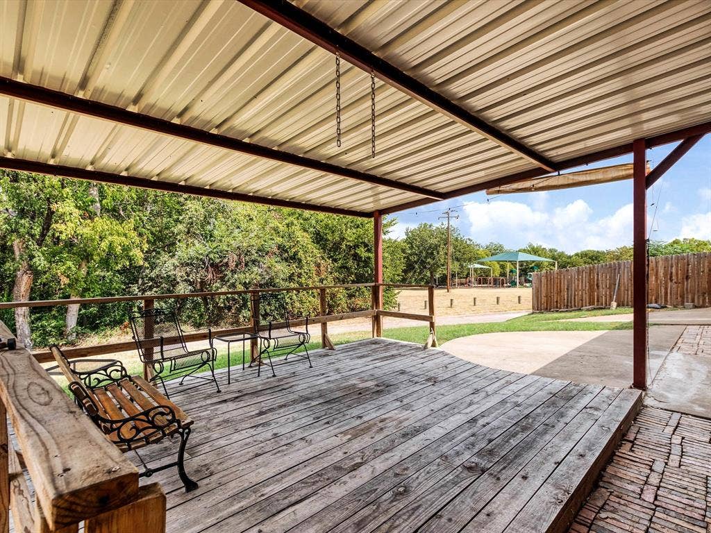 219 N Beltwoods Drive, DeSoto, TX 75115 Covered outdoor patio with a corrugated metal roof, wood-plank decking, and a wood railing