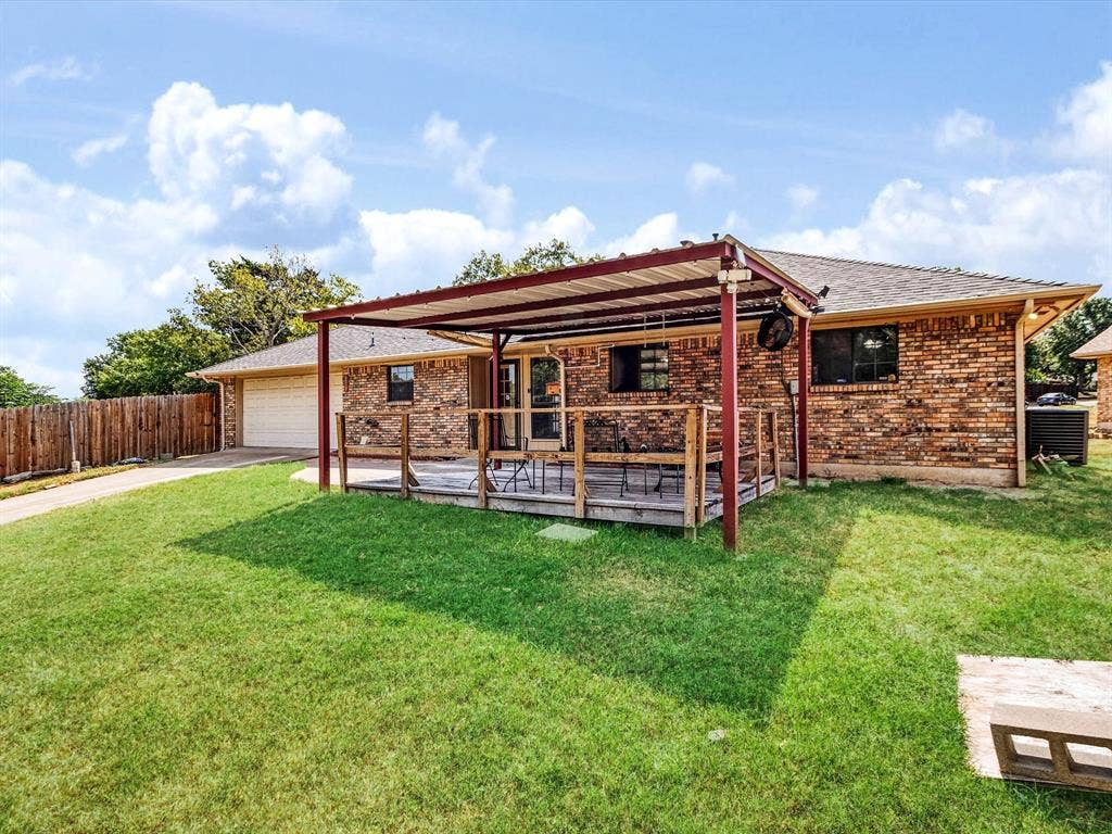 219 N Beltwoods Drive, DeSoto, TX 75115 Brick exterior with a covered wooden deck, attached garage, and a fenced yard