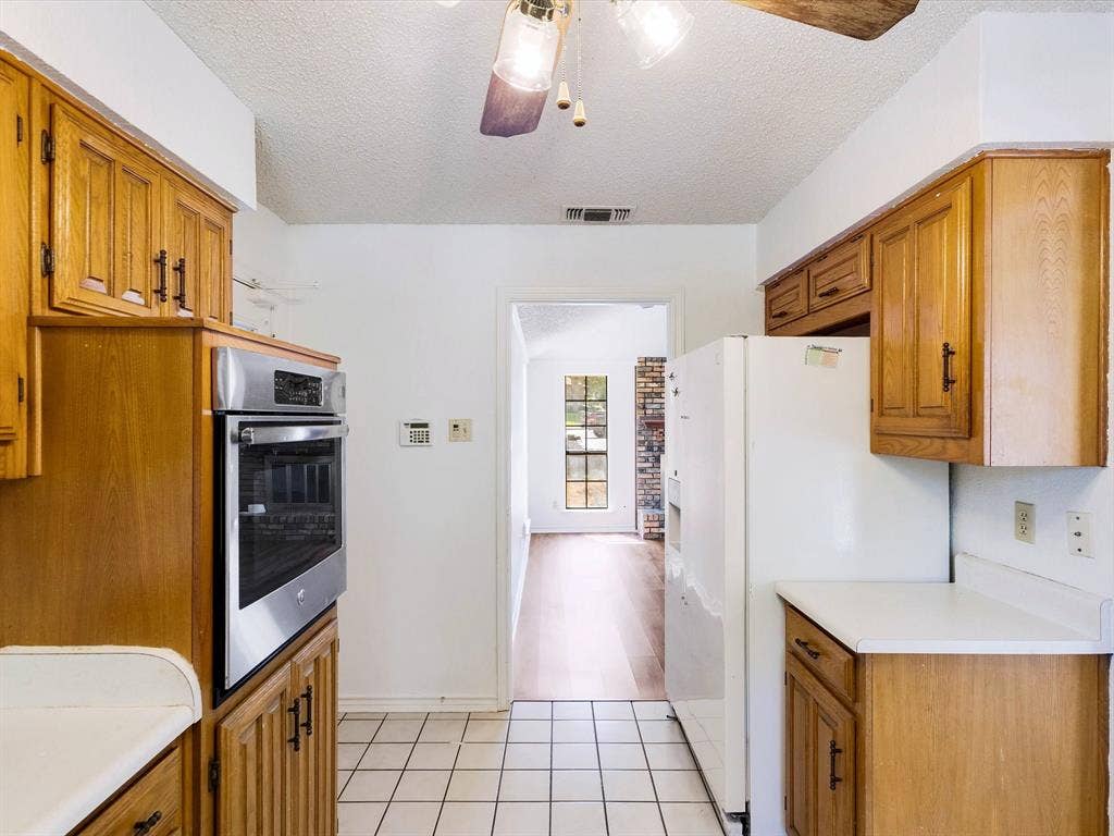 219 N Beltwoods Drive, DeSoto, TX 75115 Kitchen featuring a built-in stainless steel oven, wood cabinetry, white countertops, and tiled flooring