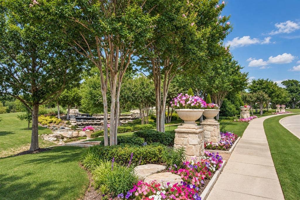 6816 Cousteau Court, Plano, TX 75024 Manicured landscaping featuring a stone water feature, mature trees, and a paved pathway