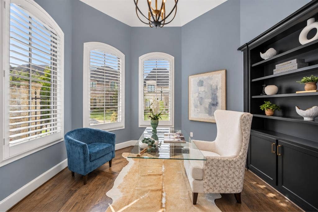 6816 Cousteau Court, Plano, TX 75024 Arched windows with plantation shutters, wood-finish flooring, built-in shelving, and a decorative ceiling light fixture