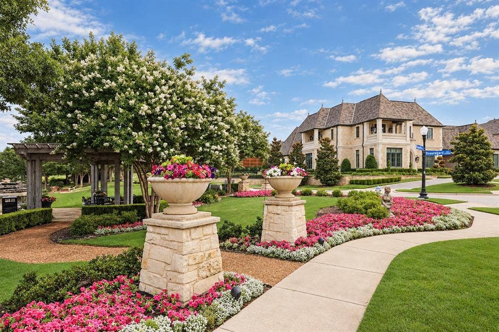 6816 Cousteau Court, Plano, TX 75024 Manicured landscaping with flowering shrubs, a paved pathway, and stone planters with vibrant blooms