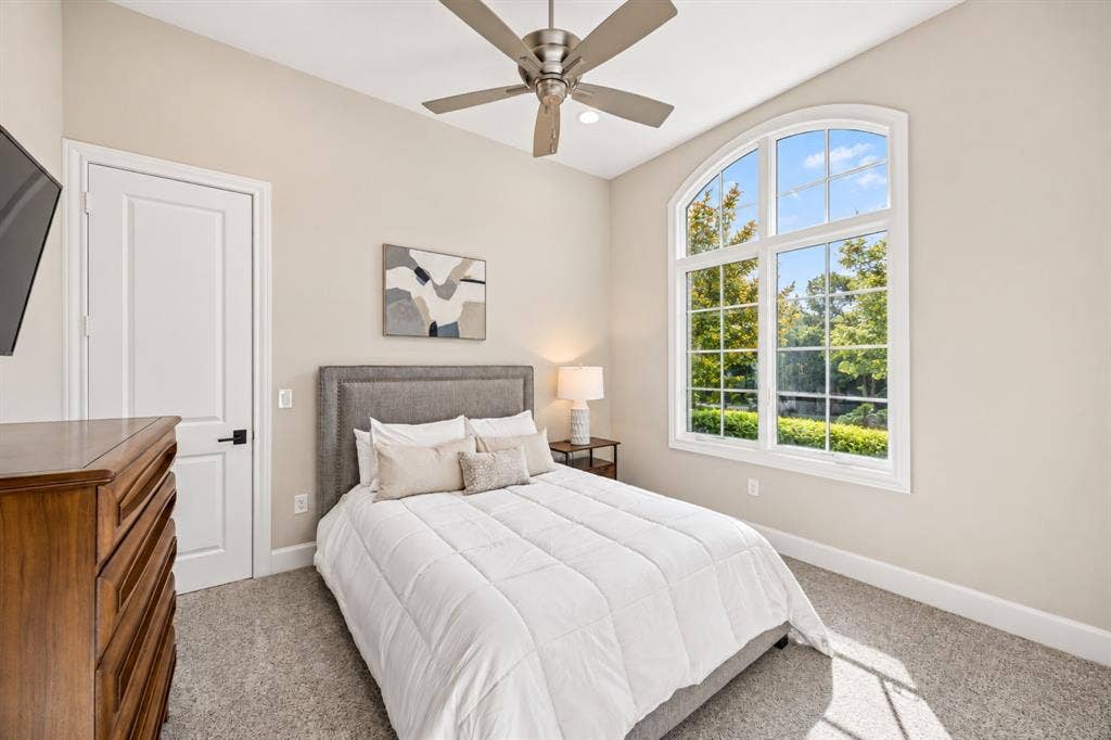 6816 Cousteau Court, Plano, TX 75024 Vaulted ceiling with a ceiling fan, arched window with gridded panes, light-toned wall paint, and gray carpet flooring
