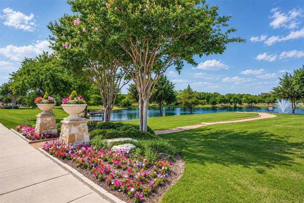 6816 Cousteau Court, Plano, TX 75024 Manicured lawn with a winding pathway, mature trees, and an ornamental water feature