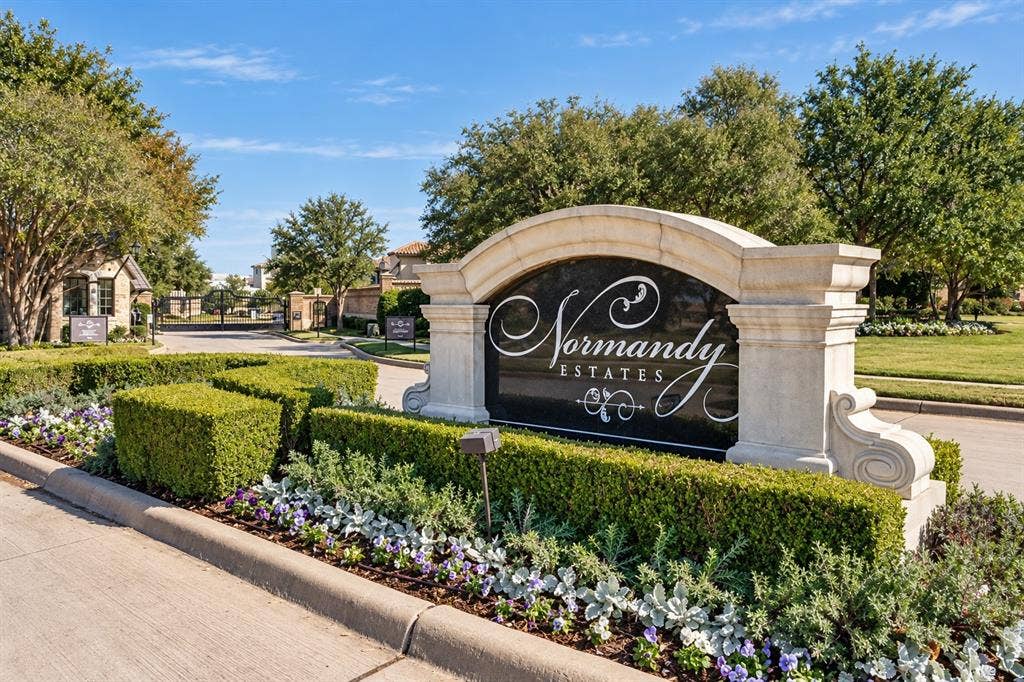 6816 Cousteau Court, Plano, TX 75024 Community entry sign with a decorative stone arch and elegant script, surrounded by manicured hedges and vibrant seasonal plantings