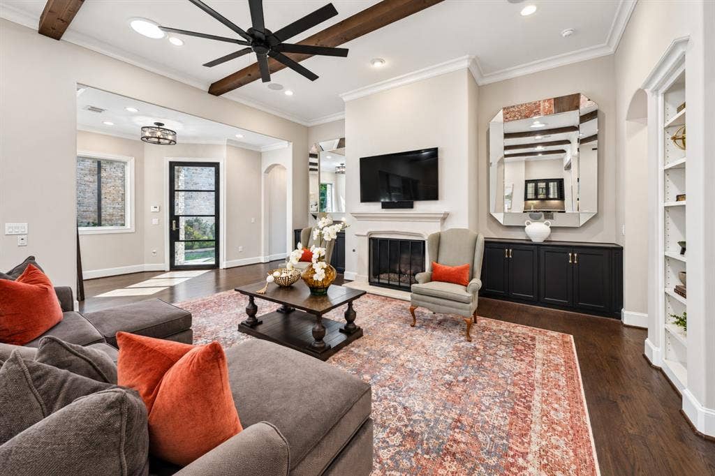 6816 Cousteau Court, Plano, TX 75024 Living area featuring dark wood-finish flooring, exposed ceiling beams, a ceiling fan, and a fireplace with a mantel