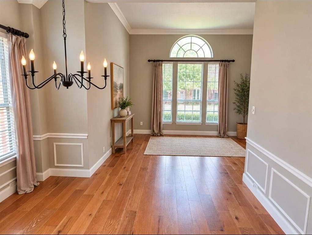 3708 Stockport Drive, Plano, TX 75025 Hardwood flooring, decorative wall paneling, crown molding, arched transom window, and a chandelier with a matte black finish