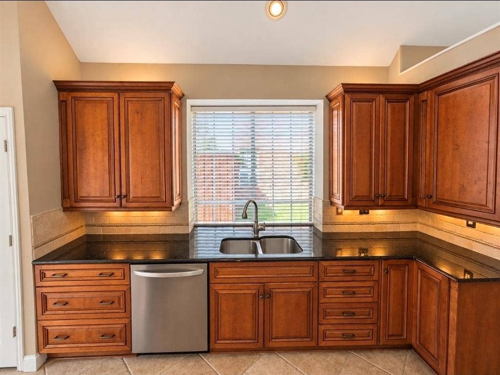 3708 Stockport Drive, Plano, TX 75025 Kitchen featuring wood cabinetry, dark countertops, tiled backsplash, and stainless steel dishwasher