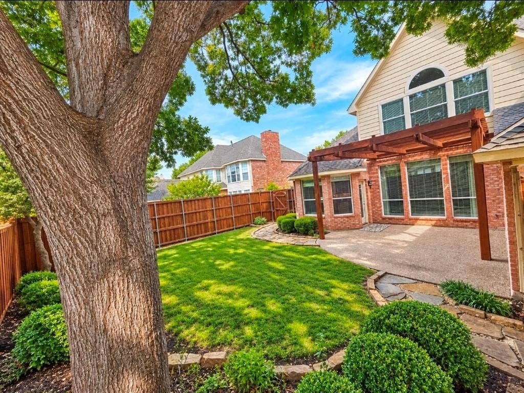 3708 Stockport Drive, Plano, TX 75025 Expansive backyard featuring a manicured lawn, established tree, and a wooden privacy fence