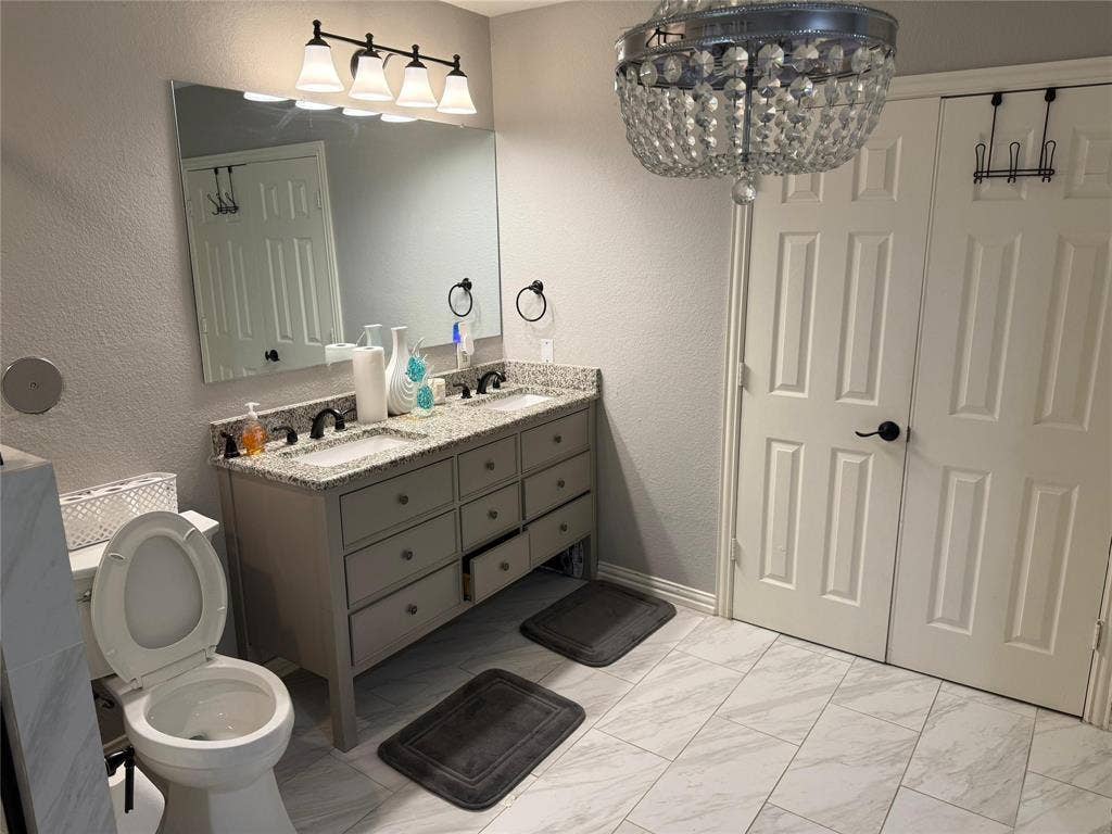 Double vanity with granite countertops, dual undermount sinks, and dark bronze fixtures