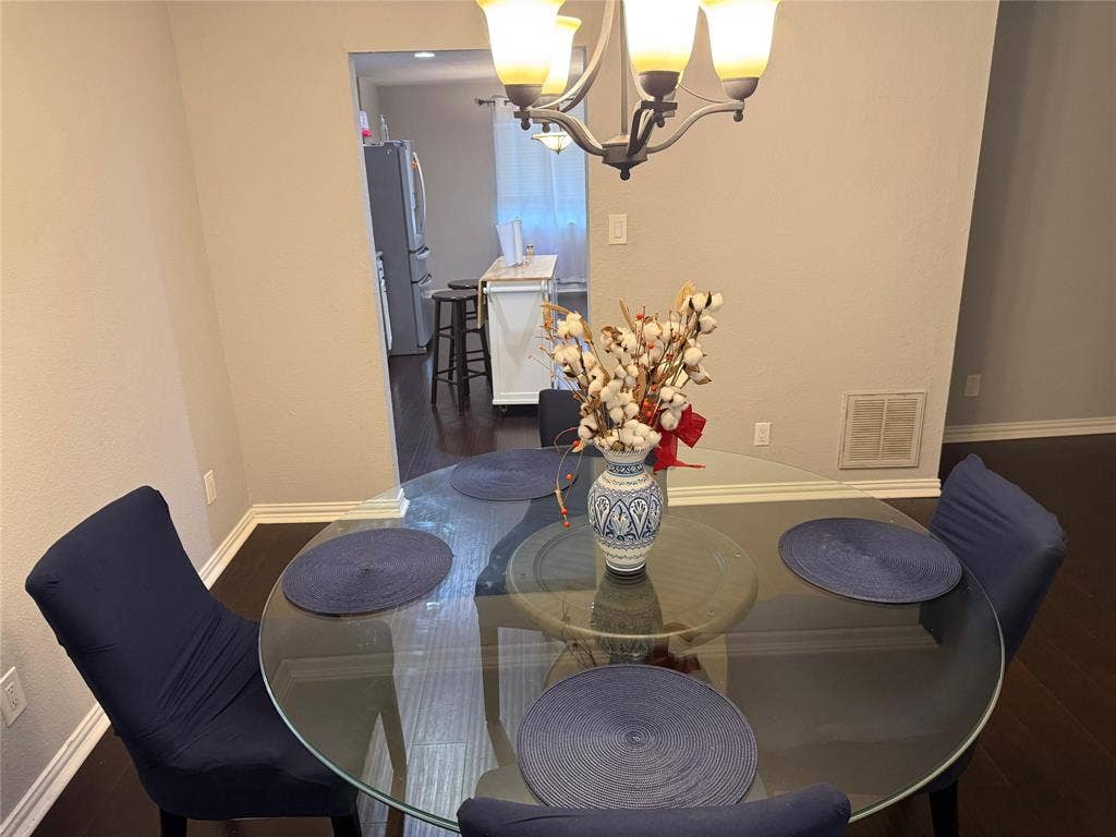 Recessed archway entry leading to a kitchen with a white island, dark wood-finish flooring, and a multi-light chandelier