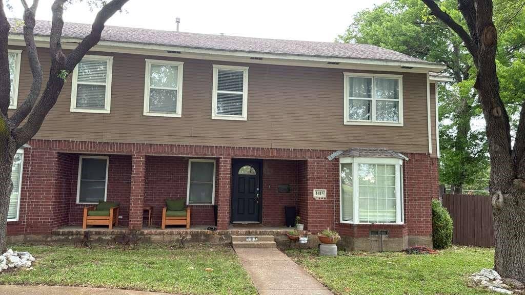 Two-story residence featuring a brick and siding exterior, a bay window, and a covered porch with brick columns