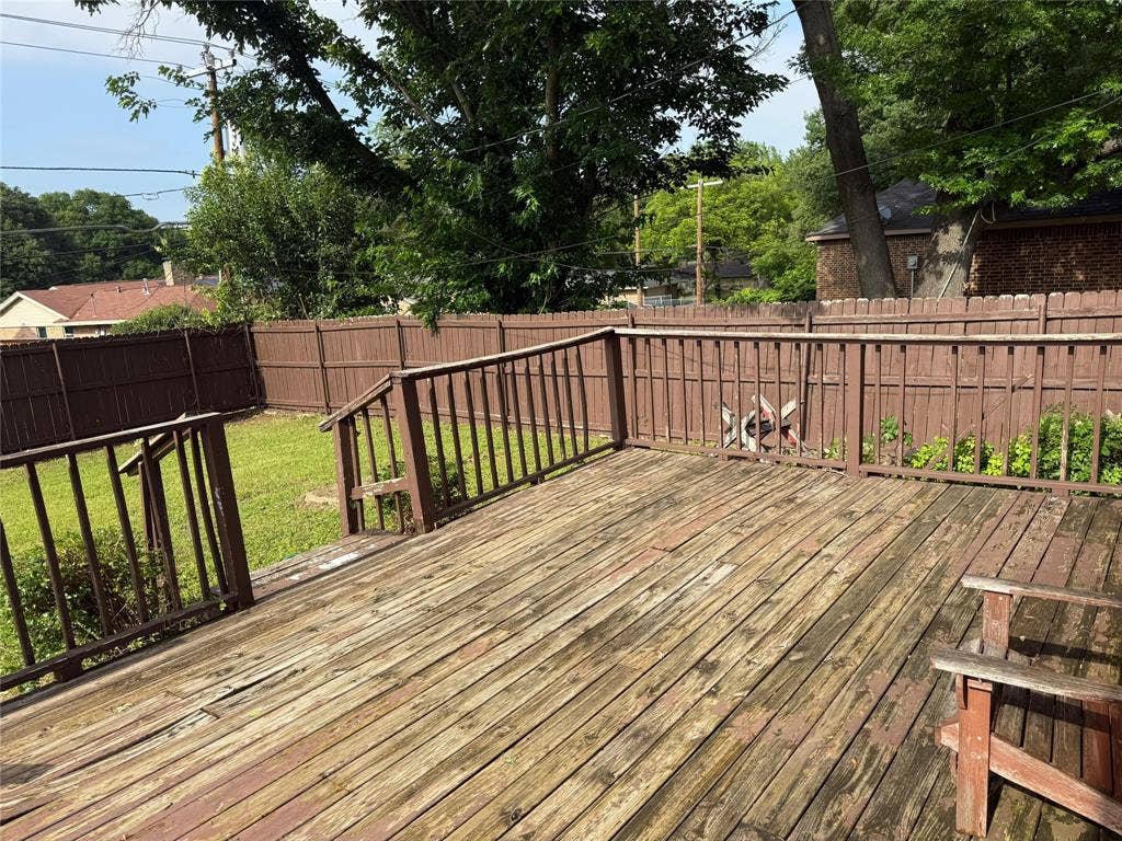 Expansive wooden deck with railings, fenced yard, and mature trees
