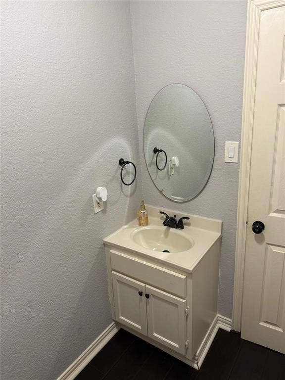 Bathroom vanity featuring a single-basin sink, dark-finish faucet, and coordinating cabinet hardware
