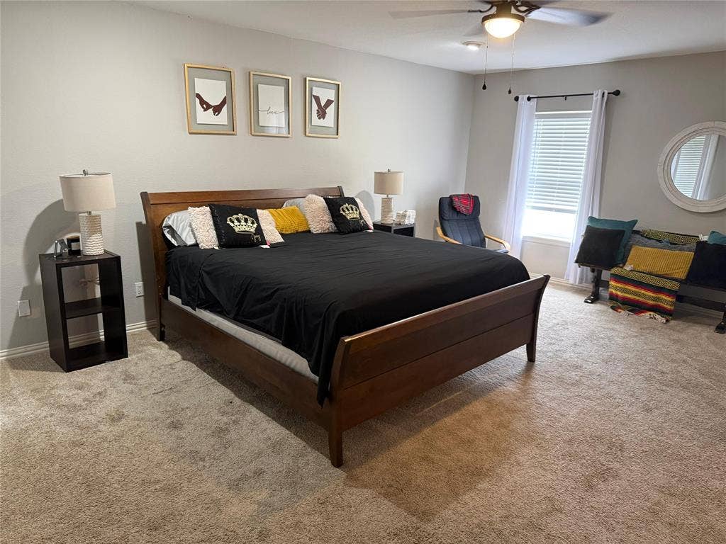 Neutral-toned wall paint, ceiling fan with integrated lighting, window with blinds and drapes, and wall-to-wall carpeting